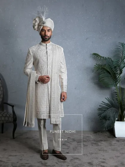 The full ensemble of the ivory silk sherwani with resham embroidery, complete with a matching stole and churidar. The zari-edged ivory turban adds a final touch of royalty and tradition.