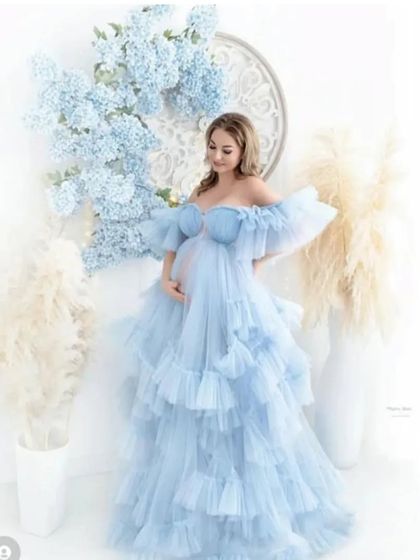 Imagine your photoshoot in this dreamy, sky-blue ruffled gown. The off-the-shoulder design and layers of soft tulle create a romantic, ethereal look, perfect for celebrating your pregnancy.