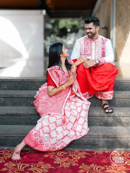 A lovely portrait of a Bengali couple in traditional attire, seated on steps.