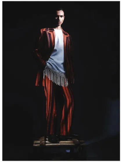 The model stands on a wooden pallet in this shot from 'Silhouette.' The elevation adds a theatrical element, enhancing the dramatic effect of the single light source.