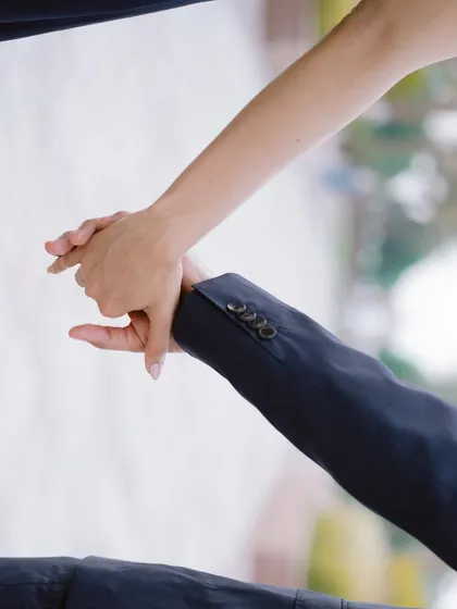 A simple, elegant detail. The close-up on their hands tells a story of connection and partnership, a small moment within a grand setting.