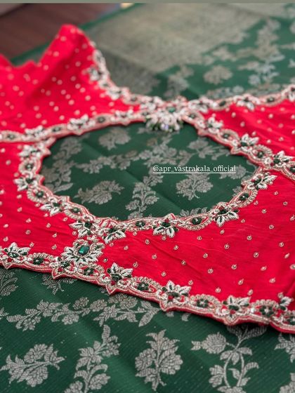 A red blouse with a sheer back, framed with green and silver embroidery.