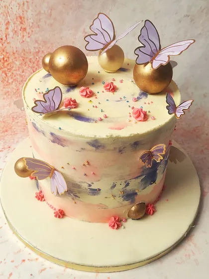 This Purple and Gold Butterfly Cake has an abstract, watercolor-like frosting base, adorned with elegant butterflies and golden spheres.