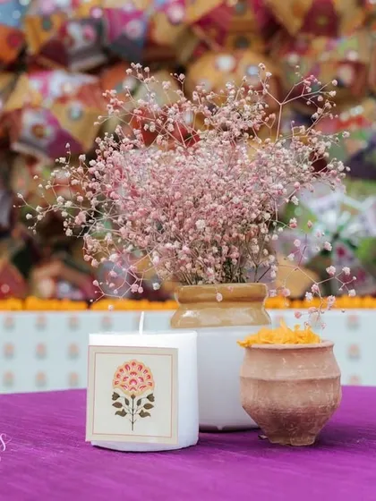 A simple yet elegant centerpiece with pink baby's breath and a candle featuring a traditional Indian motif.