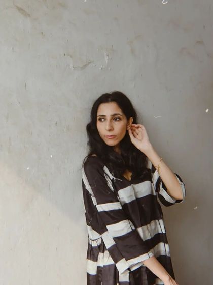 A quiet moment against a textured grey wall for House of Wandering Silk. The simplicity of the shot highlights the beauty of the garment.