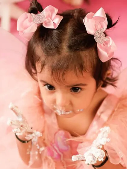 A close-up of the messy aftermath. With frosting on her hands and face, this little one shows off the pure delight of a successful cake smash.