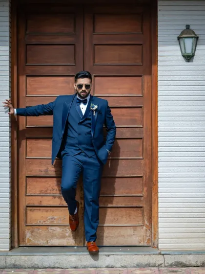 A sharp and stylish portrait of the groom. The bold blue suit and cool pose against the rustic door make for a modern and confident shot.