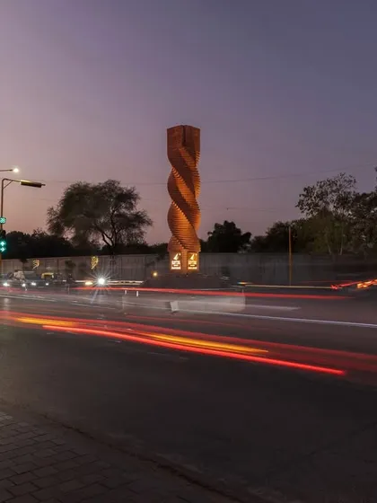 The Urban Twist sculpture at a busy Ahmedabad crossroads, seen here at dusk. This project showcases our approach to modern placemaking, using traditional brick in a dynamic spiral form to create a contemporary landmark that calms traffic and invites contemplation.