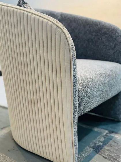 A view of the back of the two-tone armchair, showcasing the elegant curve and the detailed ribbed upholstery.