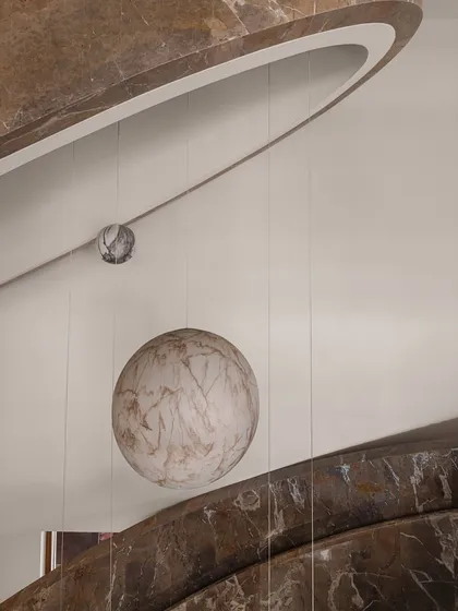 We transformed this stairwell into a surreal experience with a 'confetti carnival' installation. Oversized spheres of wood and marble are suspended by cables, and they light up in the evening to create a magical journey between floors.