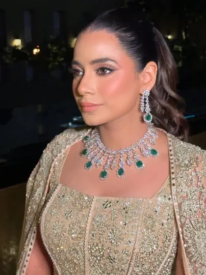 A close-up of the reception glam. The look features a flawless base, soft contouring, and a defined eye, all balanced to complement her statement emerald and diamond necklace.