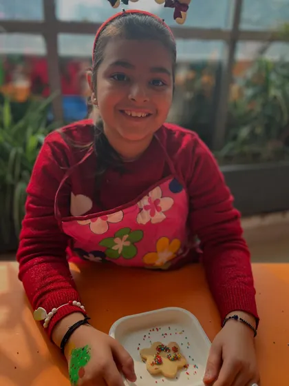 An older participant smiles proudly with her decorated cookie. Our workshops are designed to be fun for a range of ages.