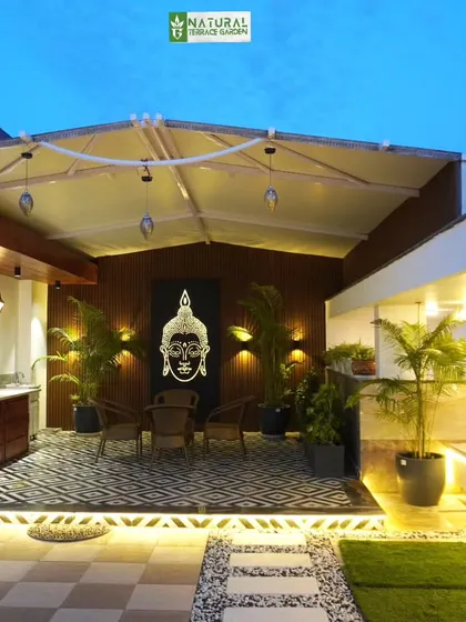 This covered seating area in Palam Vihar features a retractable awning, offering flexible shade options. The space is decorated with a Buddha panel and modern furniture.