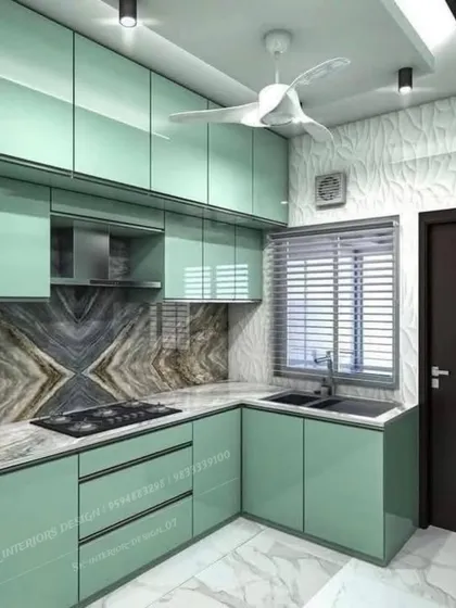 A mint-green modular kitchen with a unique book-matched marble backsplash. The design is fresh, modern, and makes the most of a compact space.