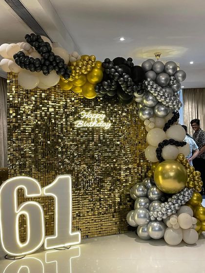 This angle showcases the full sweep of the balloon garland against the gold sequin backdrop. The mix of chrome silver, gold, and matte black balloons provides a modern and high-end feel to the birthday decor.