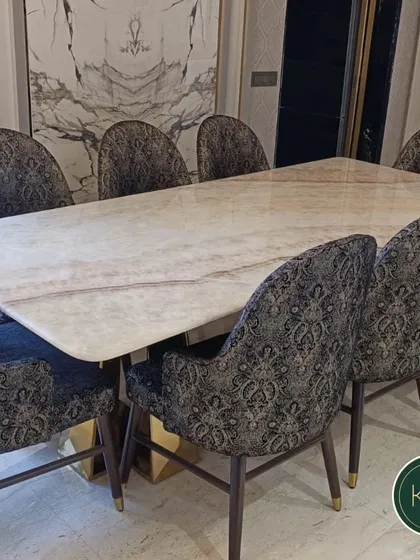 This opulent dining set features a rectangular marble table with a gilded base, surrounded by chairs upholstered in a rich, patterned fabric. It's a perfect setting for hosting lavish dinners and making a grand statement.