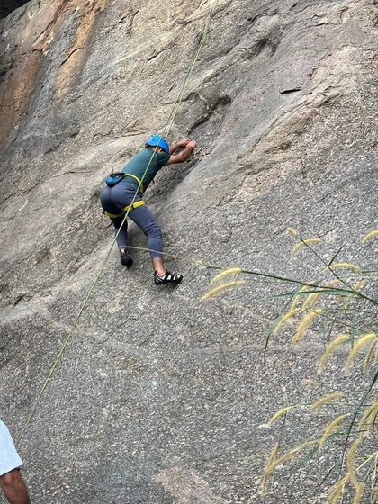 A participant in our basic course practices their climbing technique on a natural rock wall.