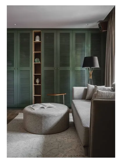 A wider view of the home theater, showing the balance between the bold green wardrobe and the neutral, calming tones of the furniture.