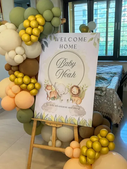 A personalized 'Welcome Home Baby Noah' sign with cute safari animals, framed by a beautiful balloon arrangement.