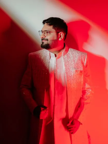 A stylish portrait of the groom-to-be, bathed in dramatic red light, looking sharp for his engagement ceremony.