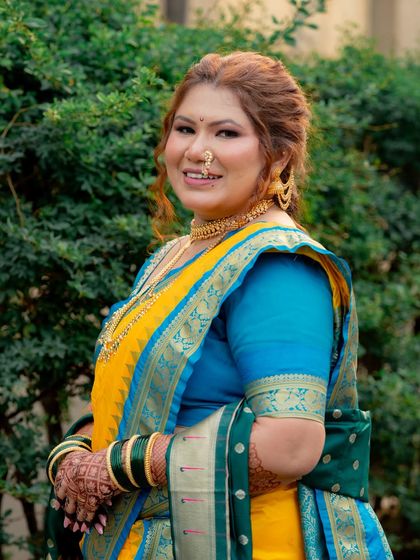 A happy bride in her yellow and blue Nauvari, ready for her big day.
