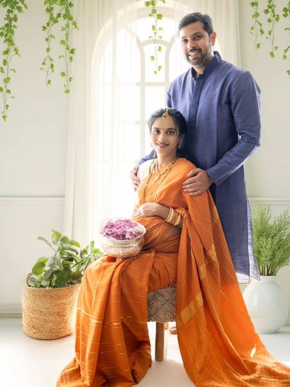 A bright and airy family portrait with the couple in traditional orange and blue outfits, showcasing a beautiful smile and connection.