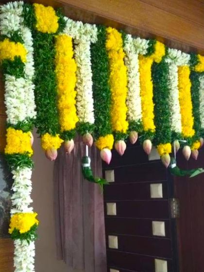 A simple main door flower decoration using garlands of jasmine, yellow chrysanthemums, and lotus buds. A beautiful and fragrant welcome for any occasion.