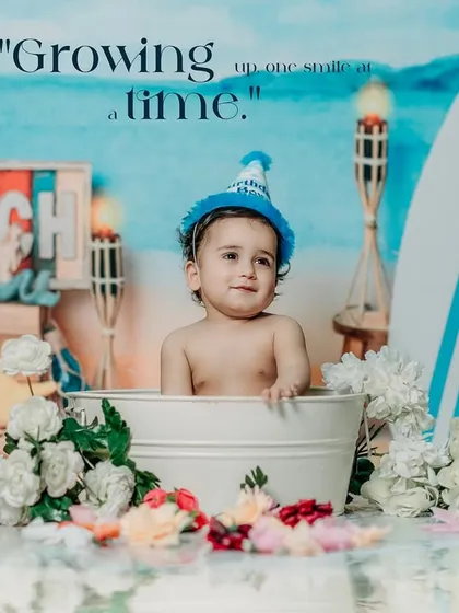 Growing up one smile at a time. A baby enjoys a bath in a tub during a fun, beach-themed studio photoshoot.