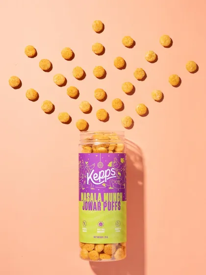We used a flat-lay composition to create a visually satisfying pattern, with the jowar puffs exploding out of the container. The color-blocked background complements the packaging and makes the entire image feel cohesive and fun.