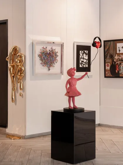 A corner of our gallery featuring the golden 'Love Drip,' a butterfly heart by David Kracov, and 'The Rhythm of Innocence.' It's art that makes you smile, pause, and think.
