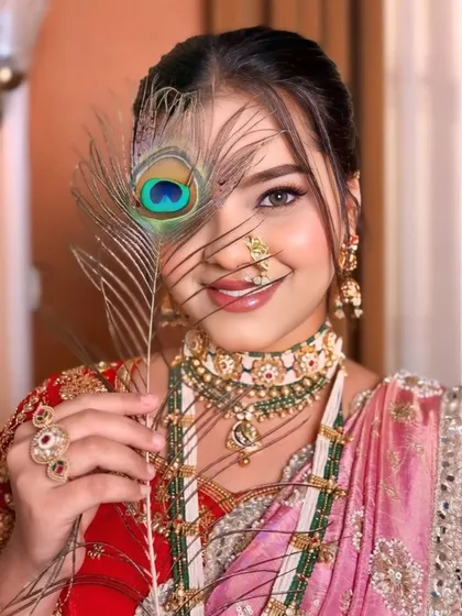 An artistic shot of a bride in a pink and red Nauvari saree. The peacock feather adds a touch of mystique to this traditional portrait.