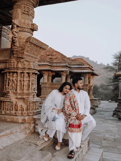 Love stories woven into the fabric of history. Here, a couple shares a quiet moment of connection amidst the intricate carvings of an ancient temple in Udaipur, blending timeless heritage with their personal narrative.