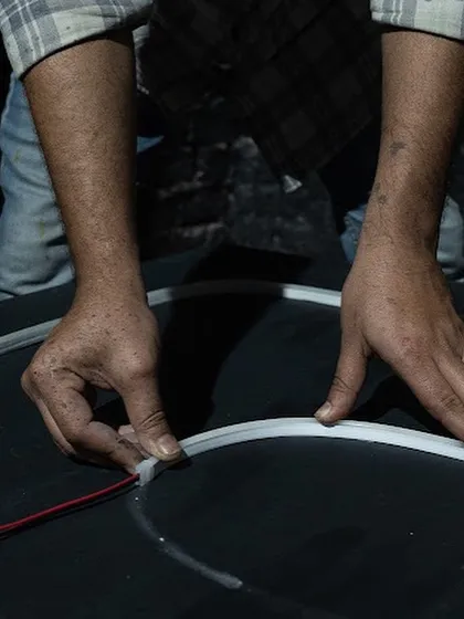 A close-up of my hands connecting the electrical components for the neon sign. This highlights the technical craft that goes into creating a large-scale light installation.
