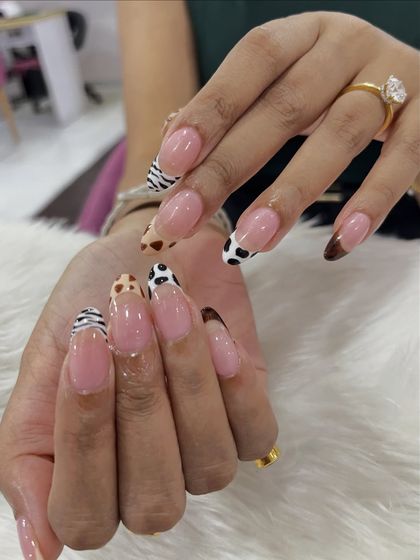 This shot captures the detail and precision of the hand-painted animal prints on these French tip extensions. Each pattern is clean and distinct.