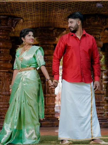 This full-length shot showcases the couple's elegant traditional outfits against a backdrop of grand, carved pillars, perfect for a heritage-themed pre-wedding shoot.