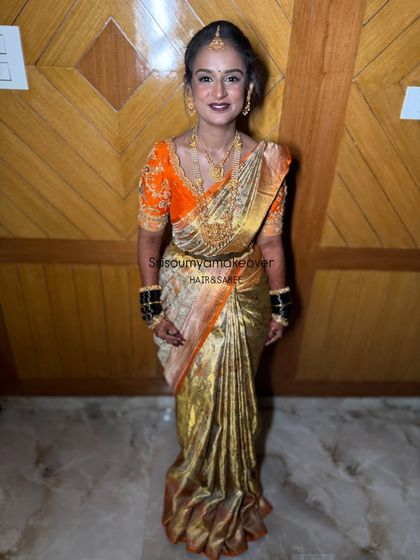 Posing with confidence and joy. This bride's full-length photo showcases her complete traditional look, from the neat hairstyle down to the perfectly pleated saree.