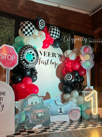 Another perspective of the car-themed decor, highlighting the balloon arch with tire and checkered flag balloons.