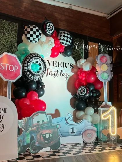 Another perspective of the car-themed decor, highlighting the balloon arch with tire and checkered flag balloons.