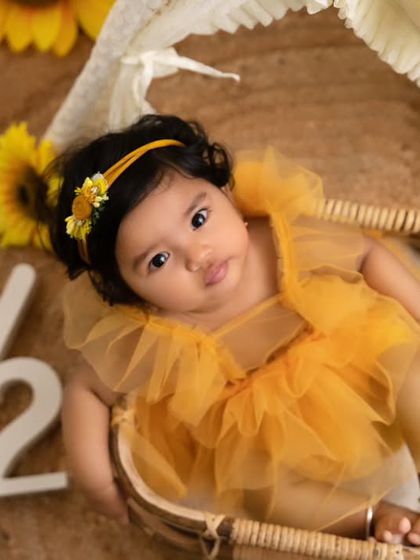 A close-up of a baby girl celebrating her half-birthday with a bright and sunny sunflower theme.