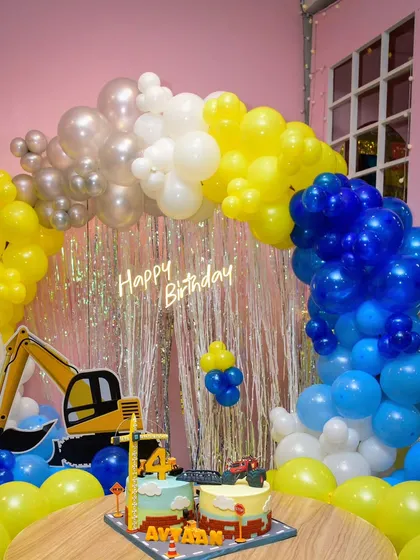 The complete construction party setup, featuring the amazing two-part cake perfectly integrated with the balloon arch and excavator decor.