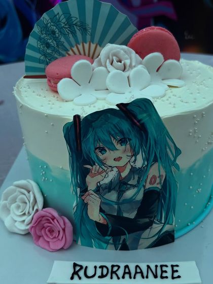 A custom anime-themed cake for Rudraanee's birthday, featuring her favorite character, macarons, and delicate sugar flowers.