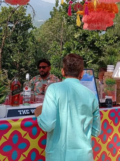 A guest enjoying our bar at a sunny outdoor wedding. The bar is decorated with bright, traditional patterns perfect for a daytime function.