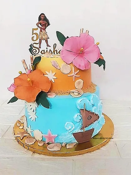 An adventurous Moana-inspired two-tier cake for a fifth birthday. The design captures the spirit of the ocean with whipped cream waves, edible sand, and tropical sugar flowers, all without relying heavily on fondant.