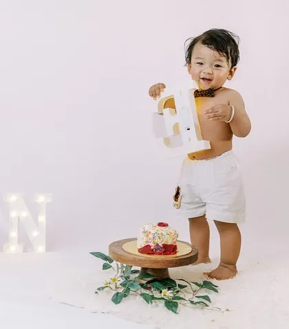 The birthday boy is ready for his cake smash. This shot captures the anticipation before the messy fun begins.