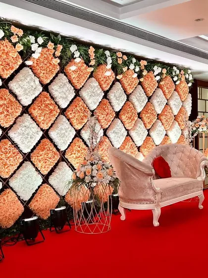 This angle shows the beautiful interaction between the floral wall, the elegant chaise lounge, and the side floral arrangements, creating a cohesive and luxurious look.