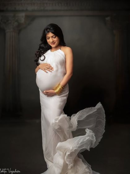 A standing portrait in a flowing white halter gown. The gold cuff adds a touch of modern elegance to this classic look.