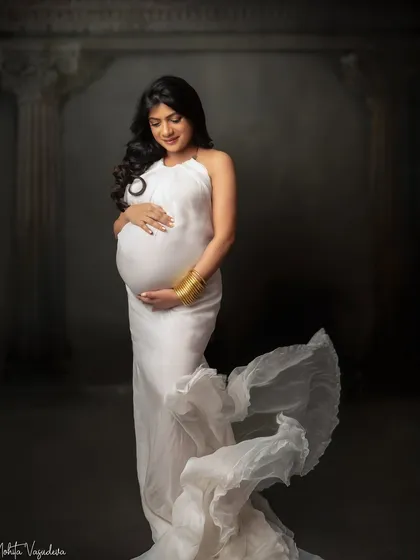 A standing portrait in a flowing white halter gown. The gold cuff adds a touch of modern elegance to this classic look.