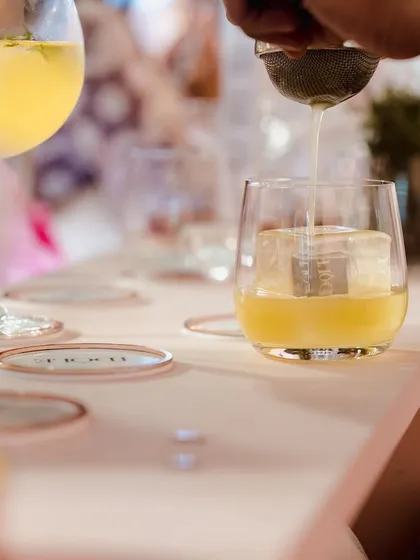 A bartender preparing a custom cocktail with a large, clear ice cube. For the launch of Lancôme's Idôle, we created a bespoke bar menu with personalized garnishes to set the tone.