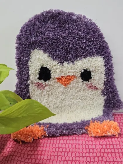 A close-up of the super cute purple penguin rug made during a family workshop. The fluffy texture and sweet design make it a perfect piece of handmade decor.