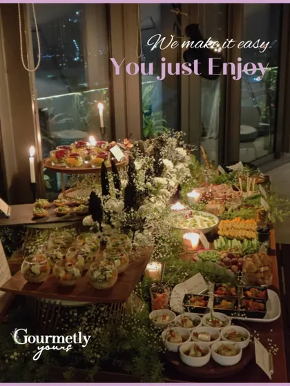 An atmospheric shot of a candlelit grazing table set against a city skyline at night. This image perfectly captures the mood of a sophisticated evening event, where we make hosting easy so you can enjoy the moment.